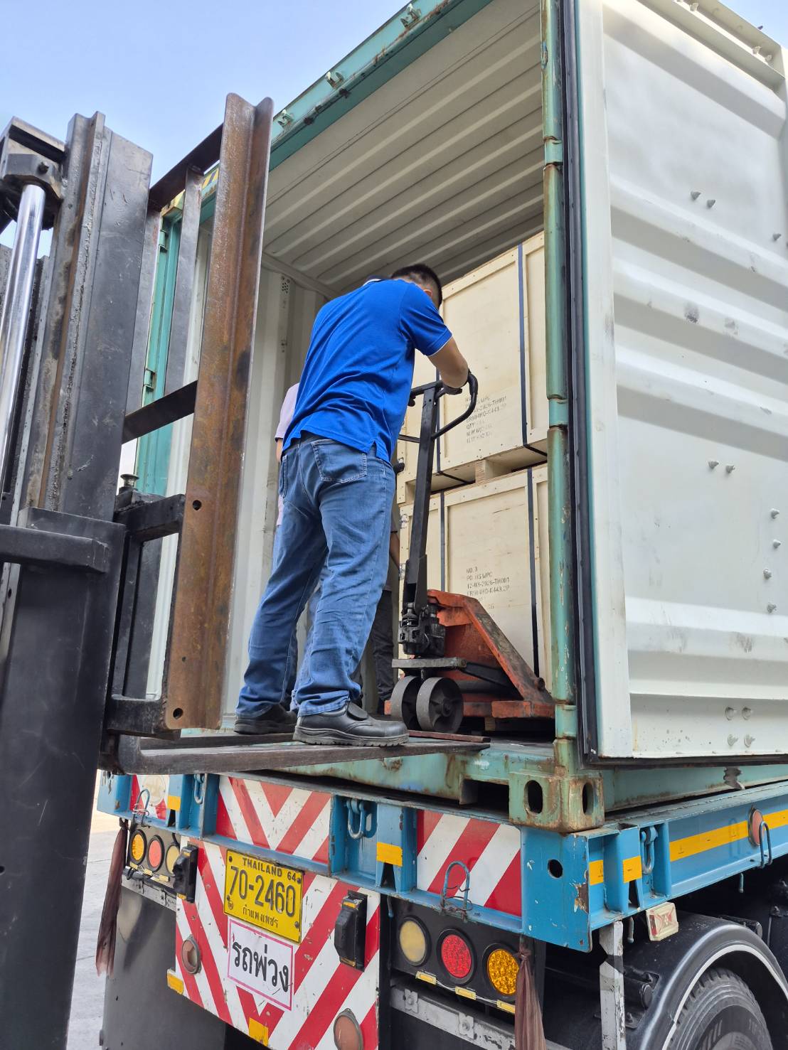MPC technician operating pallet jack inside shipping container during chain delivery